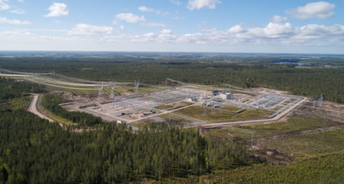 Ilmakuva metsän ympäröimästä sähköasema-alueesta. Alueella näkyy voimajohtoja, teräsrakenteita ja työmaateitä.